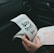 A person is holding and examining what appears to be lottery tickets inside a car. The image is focused on the tickets and the person's hands, with parts of the car interior visible in the background.